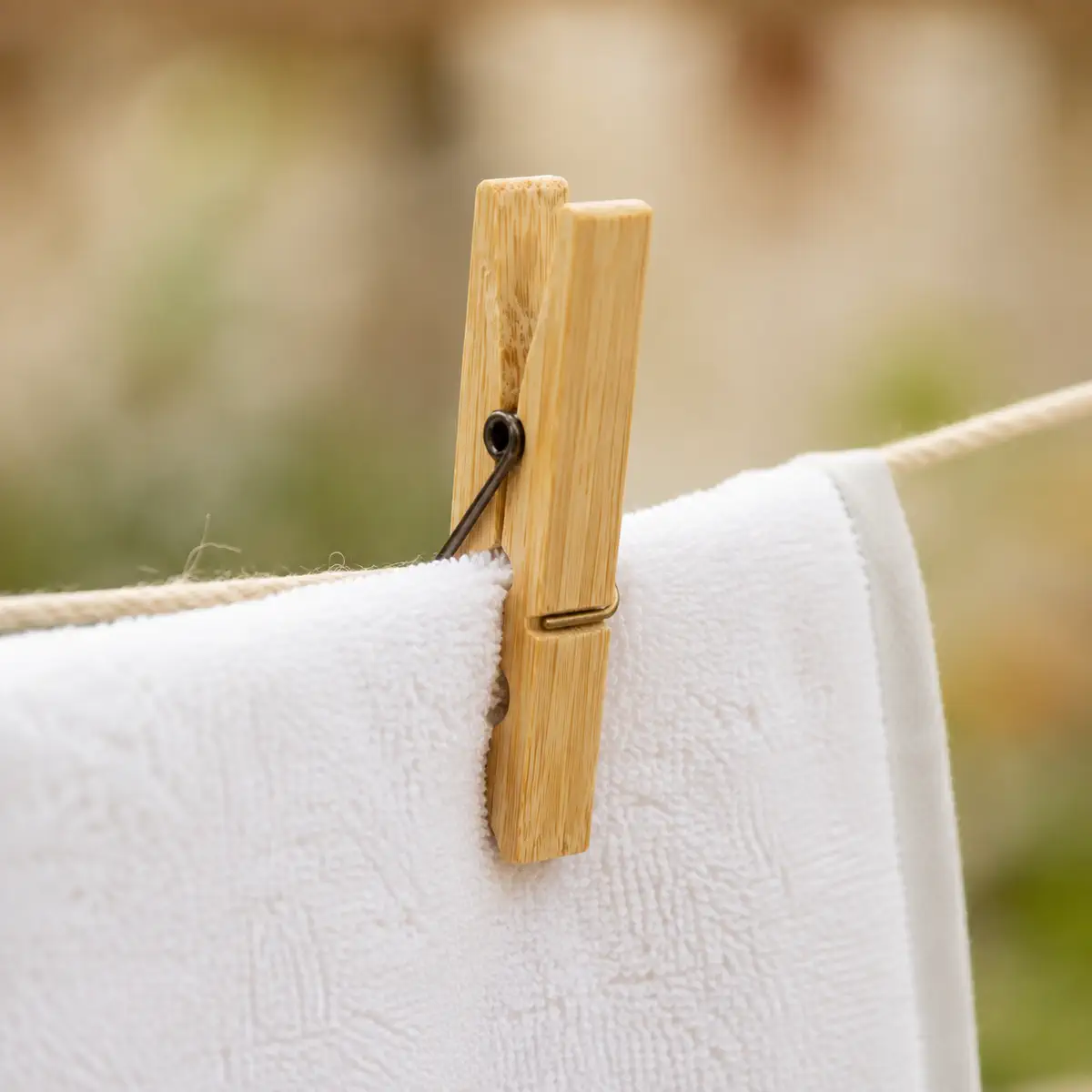 Bamboe wasknijper houdt handdoek aan waslijn vast