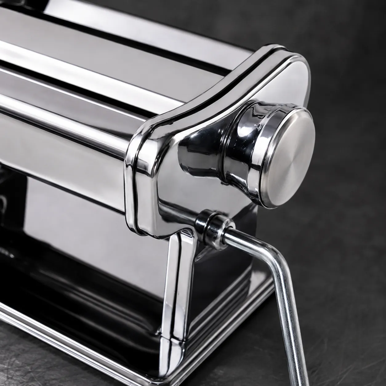 Detail van rollers, instelknop en slingerbevestiging van RVS pastamachine