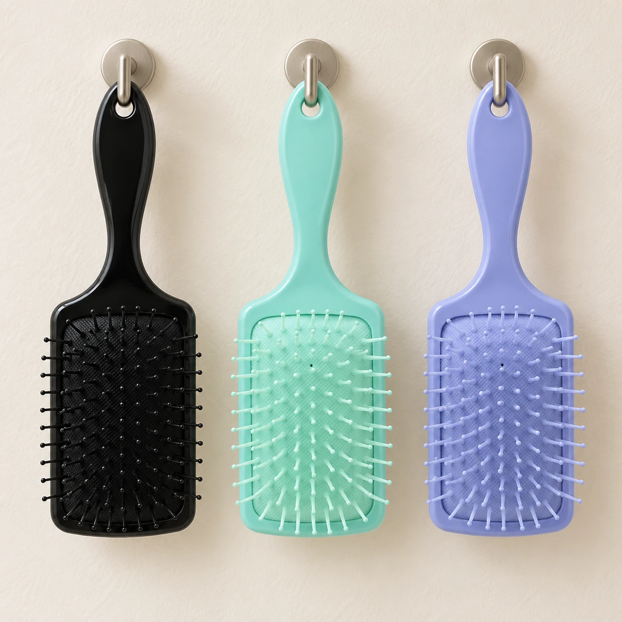 Drie Elina Hair haarborstels hangen aan hun ophangoogjes: zwart, mintgroen en lila